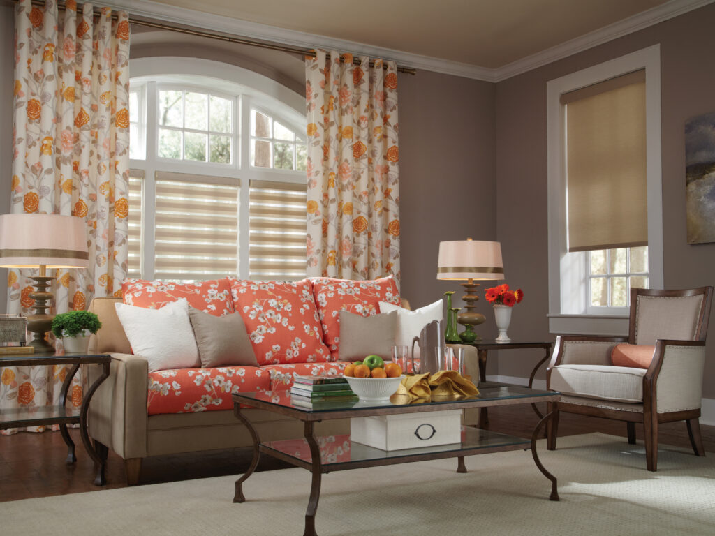Band shade and roller shade combination installed in a traditional living room with floral curtains in Bridgeland, TX