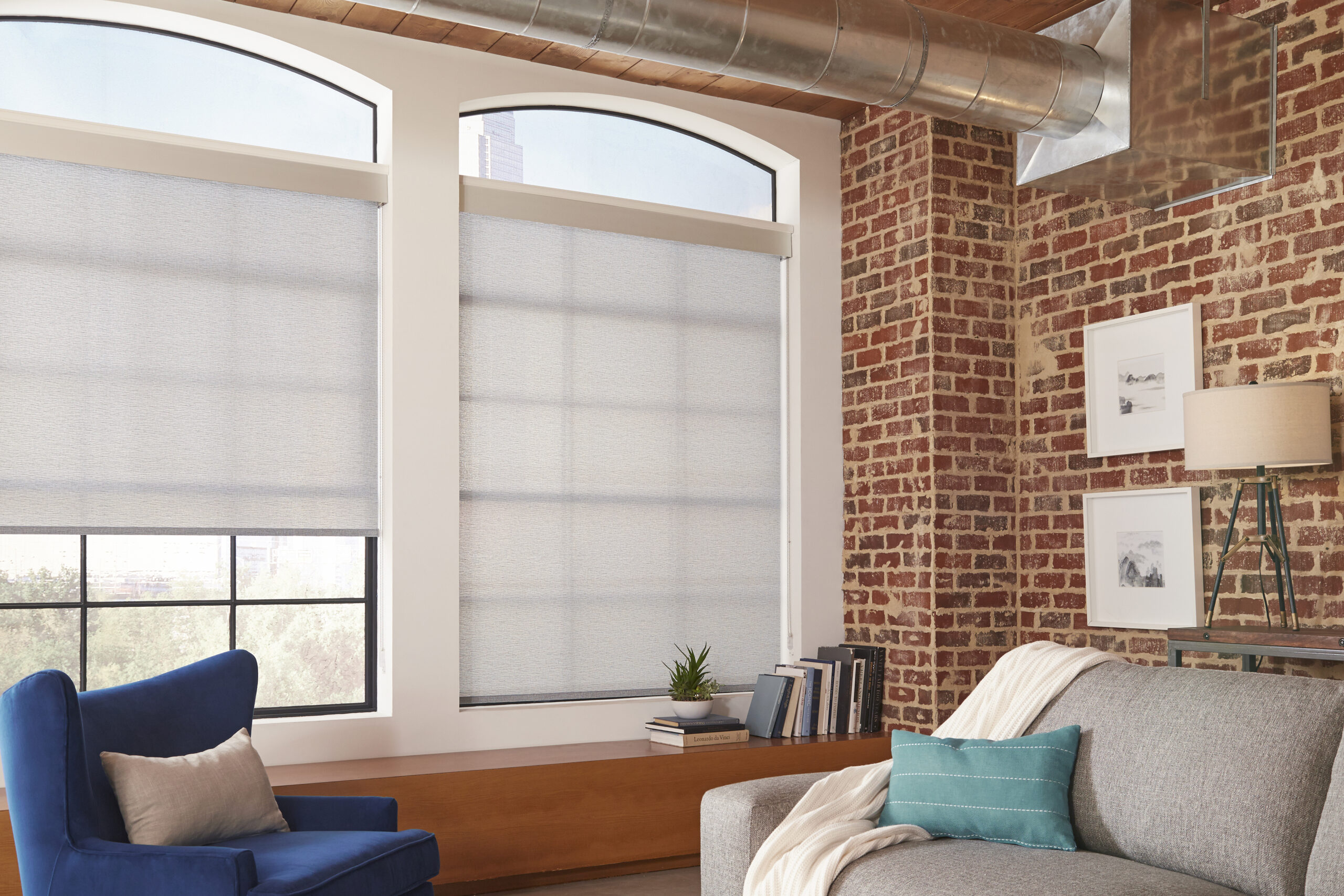 Roller shades in a warm living room with exposed brick wall in Bridgeland TX